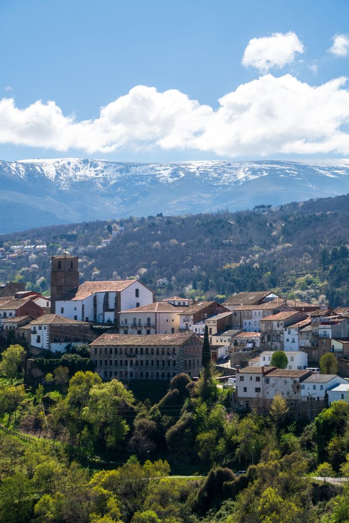 A scenic view of a quaint Spanish town with a mountainous backdrop and lush greenery.