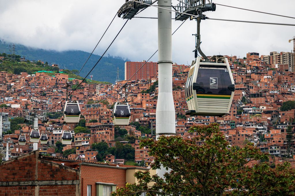 Cable cars traversing the vibrant hillsides of Medellín, with terracotta buildings and lush greenery below.
